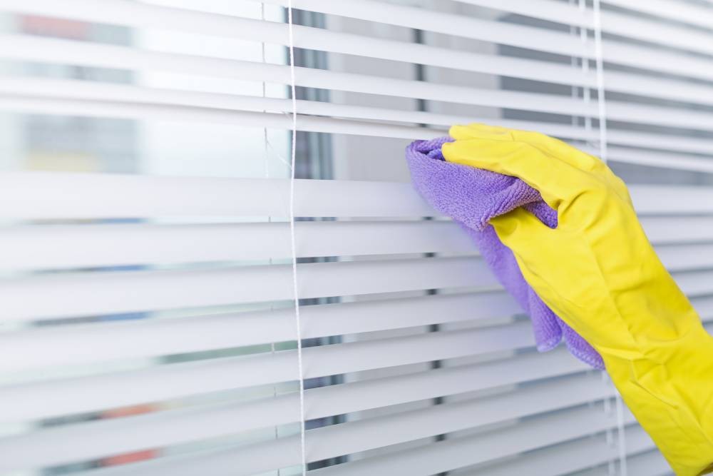 A cleaner cleaning blinds with a cloth near Mount Pleasant, South Carolina (SC)